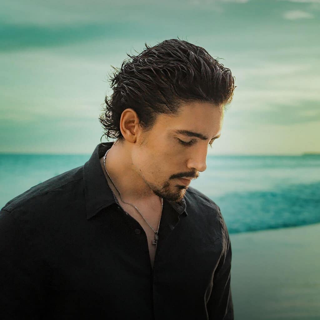 Retrato de Alex Fernández en la playa, con camisa negra y mirada introspectiva.